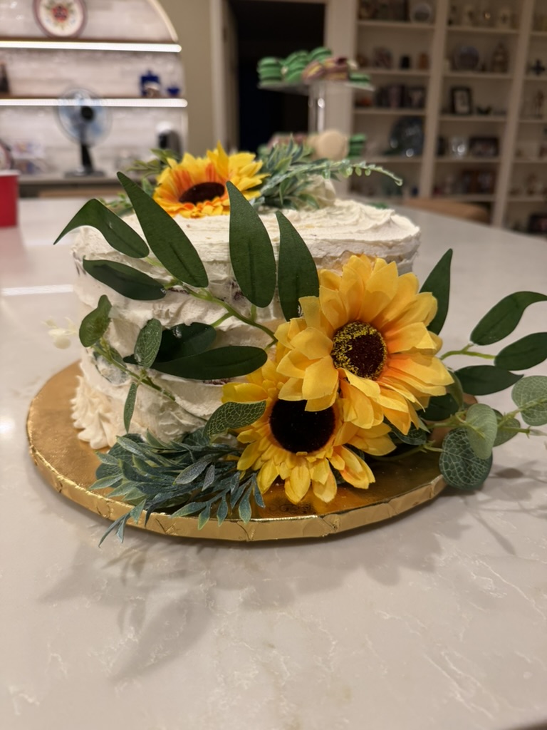 Celebration cake decorated with bright sunflowers and greenery